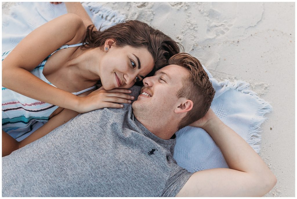 Couple laying down in sand during beach photos at Johnson beach in Perdido Key, FL. Pensacola Couple Photographer