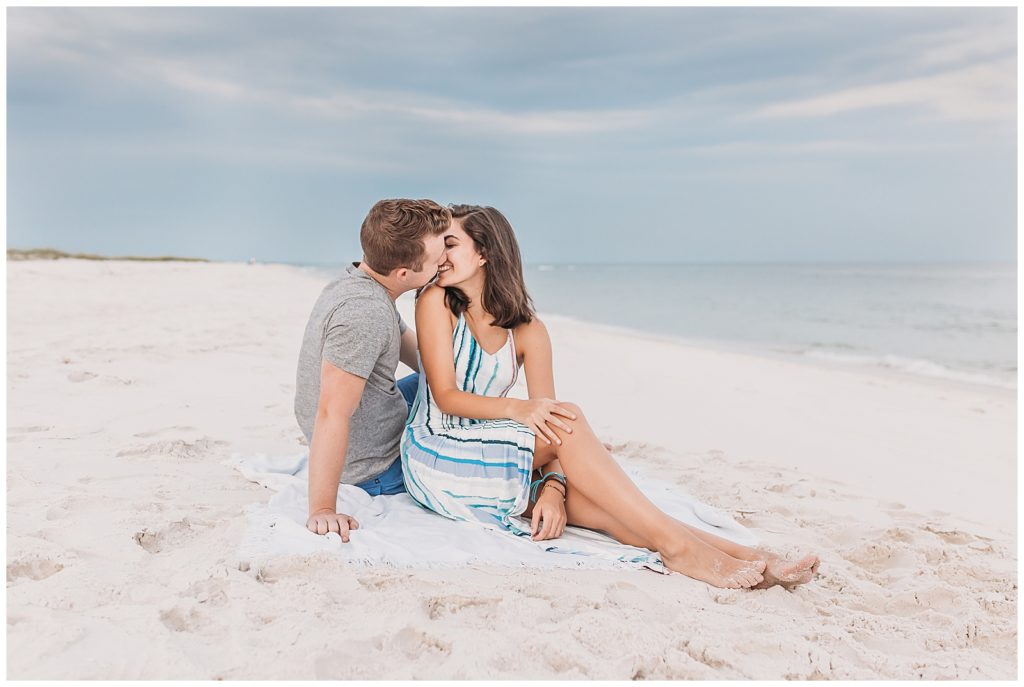 Engaged Couple Sitting on Pensacola Beach which is an excellent engagement photoshoot location.