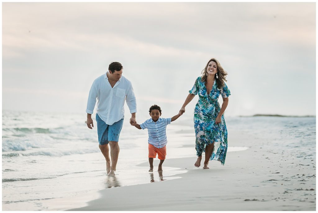 Family running near water during Pensacola Beach family photo session. Pensacola Beach Photography