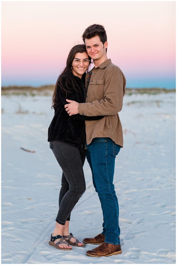 Young couple on Pensacola Beach during beautiful pink and purple sunset. Pensacola Photographer