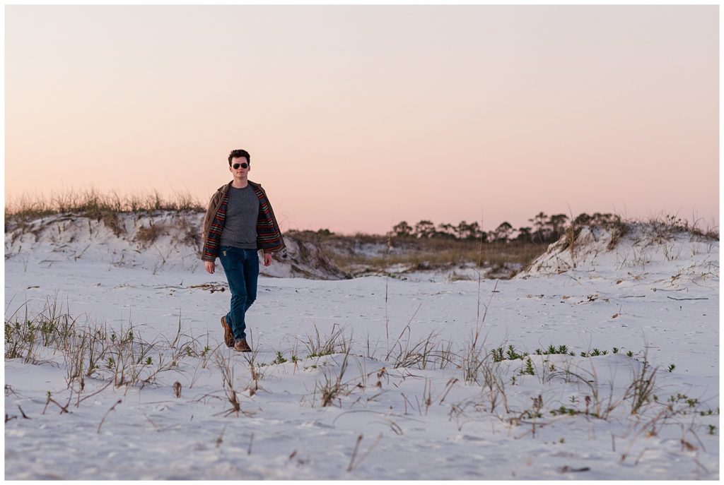 Man walking in front of the white, sandy beach dunes on Pensacola Beach. Pensacola Beach Photography