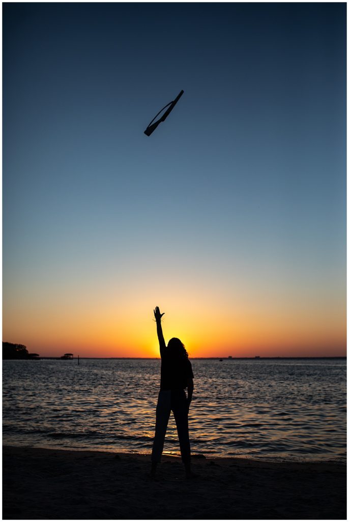Senior girl sunset silhouette photo with color guard rifle in the air high above. Pensacola Senior Photographer, Jennifer Beal Photography. 