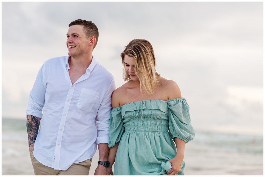 Newly engaged couple walking down Pensacola Beach during engagement photo session
