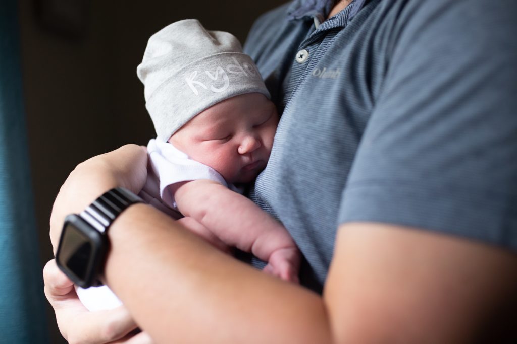 Lifestyle newborn photography session with the baby boy lying on dad's chest.