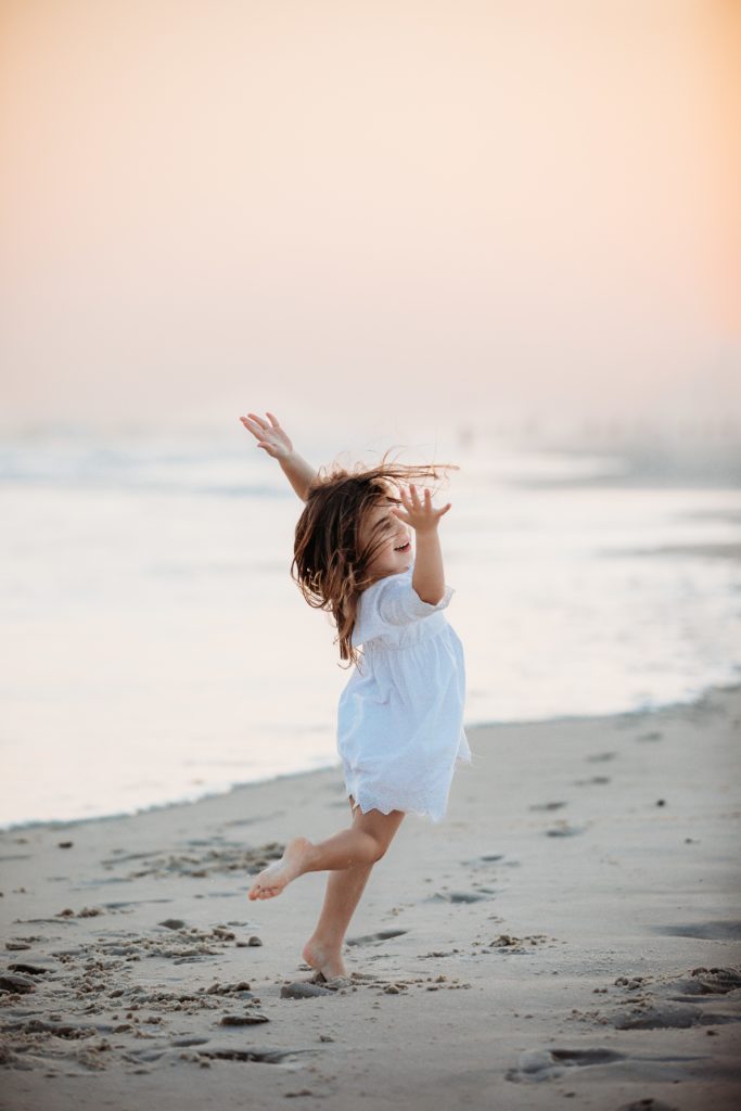 Young Girl spinning around during Pensacola Beach photos.