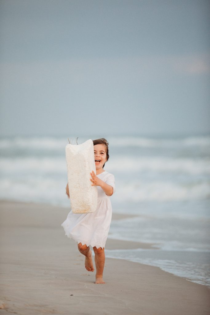 Pensacola Beach vacation tips - Leave No Trace. Young girl running with a large piece of styrofoam she pulled out of the Gulf. She was so excited to help the sea life. 