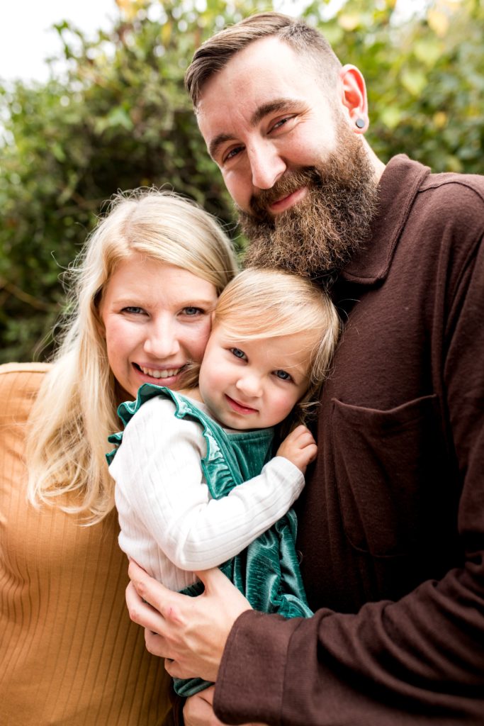 Cozy family of three cuddling during photos at Fort Pickens.