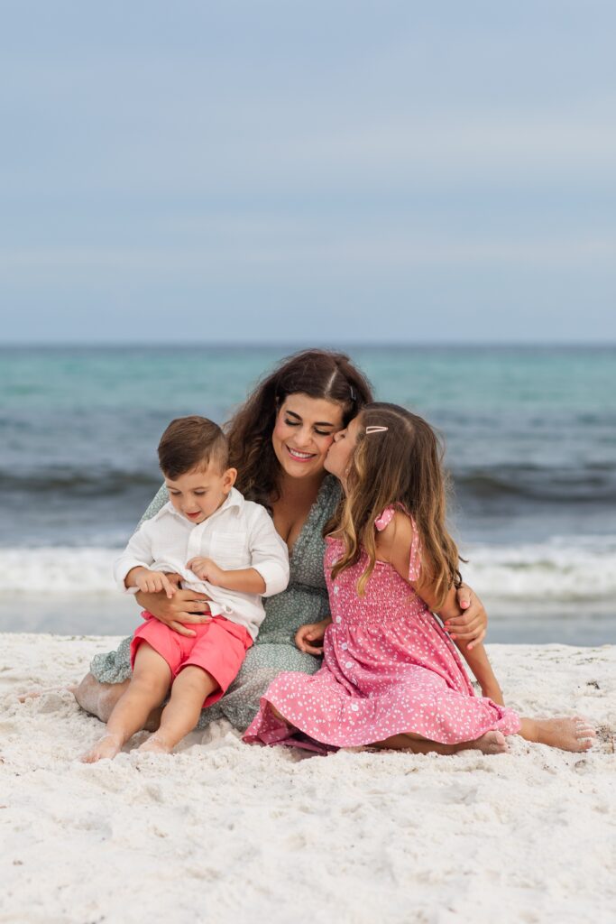 Mom embracing children on Pensacola Beach during family photo shoot.