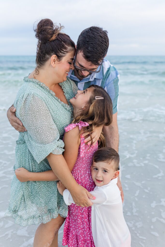 A photographer in Pensacola captures vacationing family hugging on the beach at sunset. 