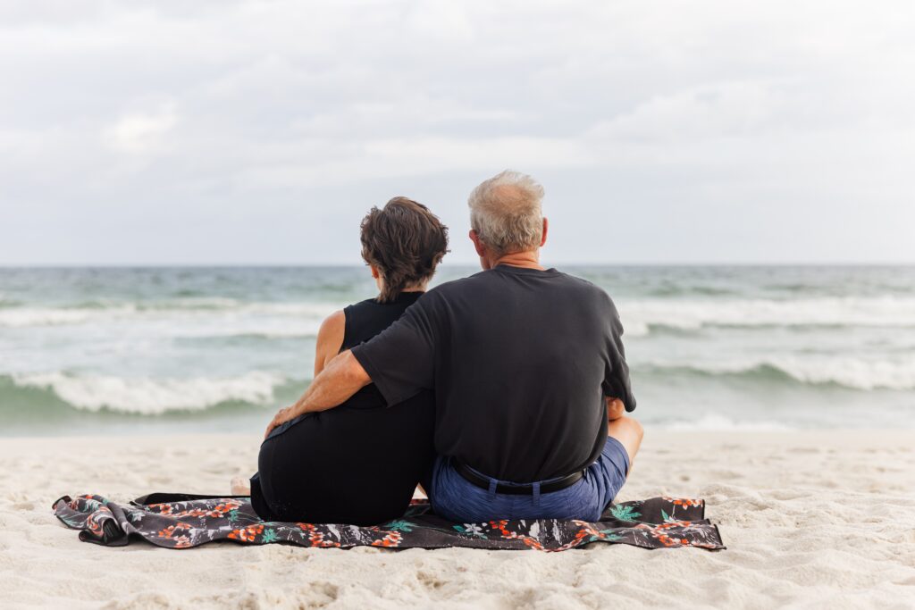Older couple sitting on Pensacola Beach watching the waves during an extended family photo session. Finding a family photographer