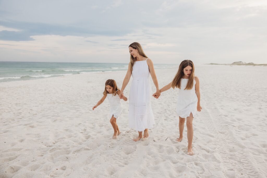 Mom walking down beach with daughters during family photo session on Navarre Beach. Photos by Pensacola Photographer, Jennifer Beal. 