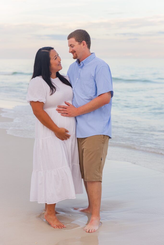 Expectant couple posing on Pensacola Beach