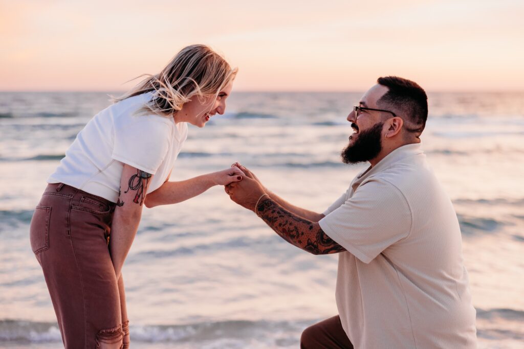 Surprised girlfriend leaning down to say yes during sunset surprise proposal session by Jennifer Beal Photography.