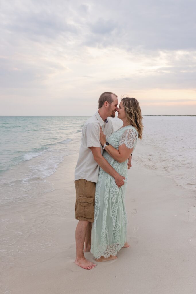 Couple embracing on Pensacola Beach during sunset photo session by Jennifer Beal Photography.