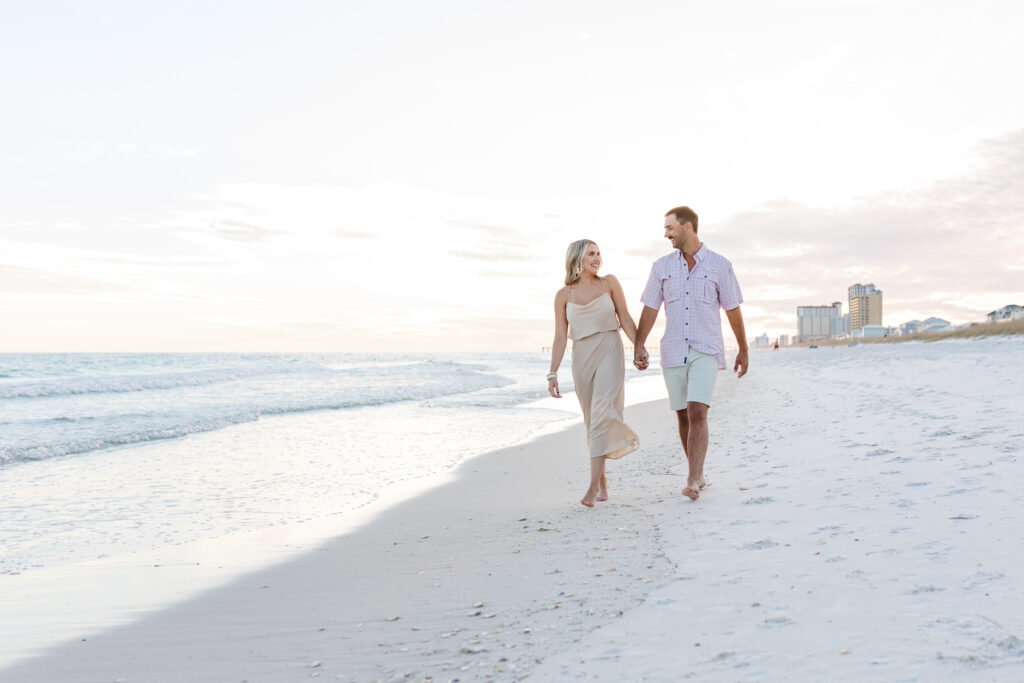 Couple walking down Pensacola Beach at sunset