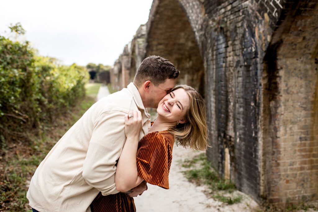 Couple hugging with Fort Pickens in the background. 