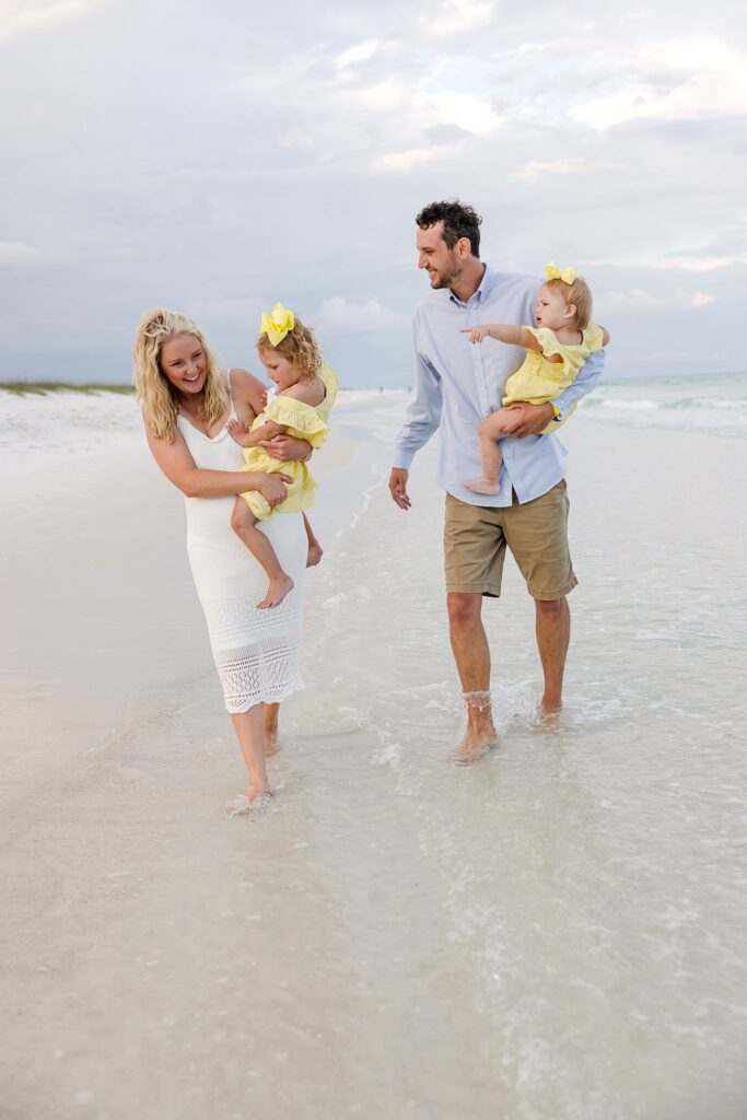 Family with toddlers walking down Pensacola Beach at sunset