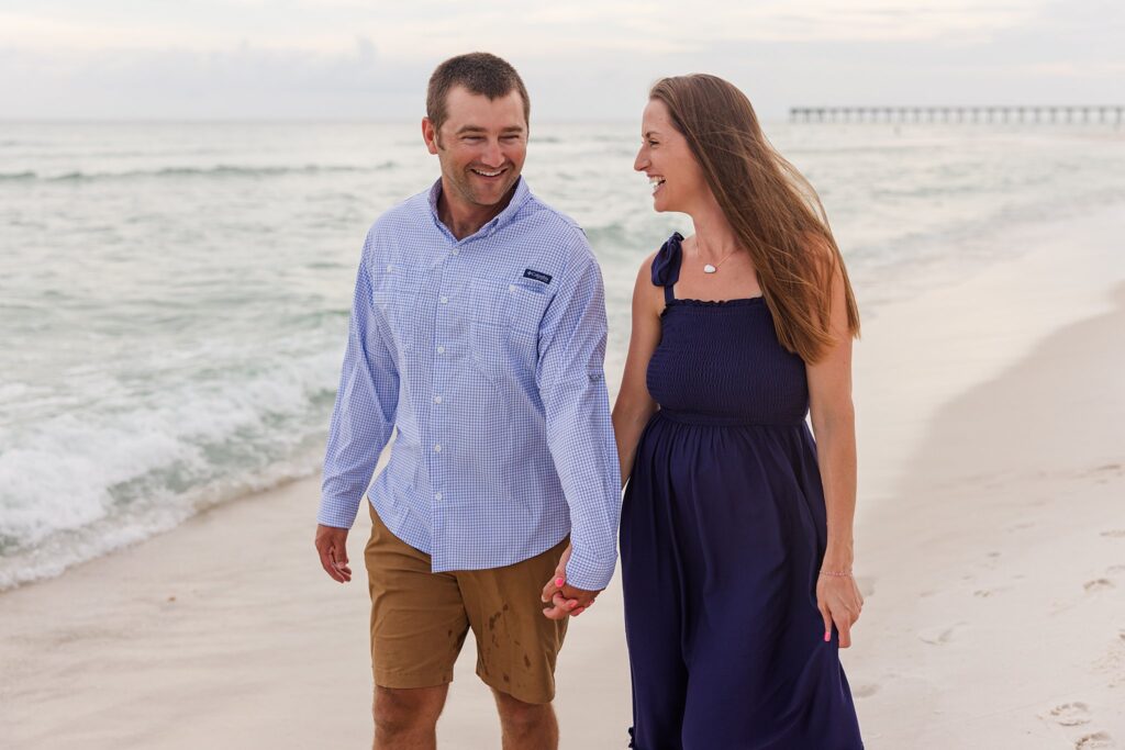 Couple walking down Pensacola Beach during family photo session by Jennifer Beal Photography
